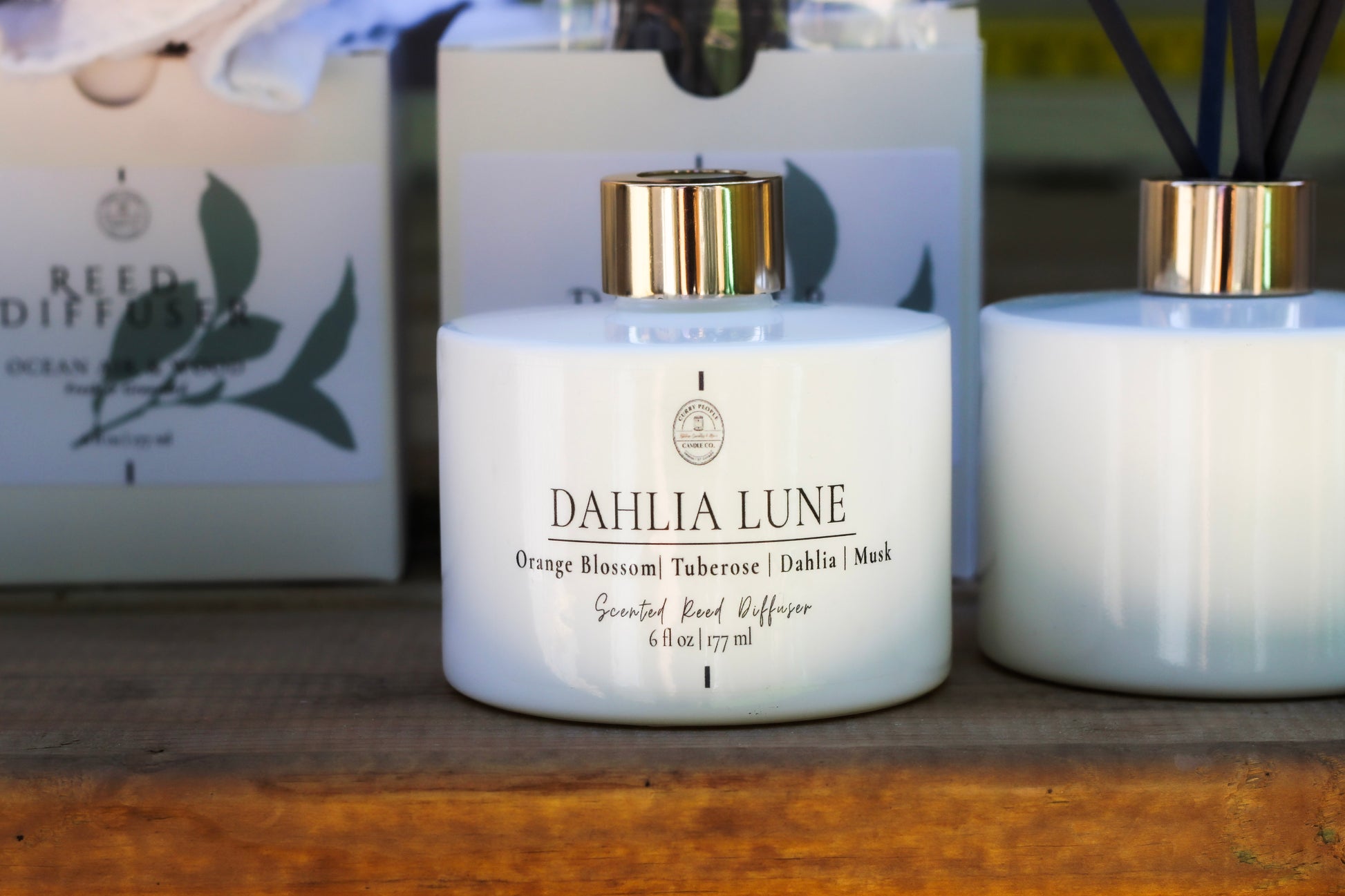 Dahlia Lune candle with a diffuser and packaging in the background