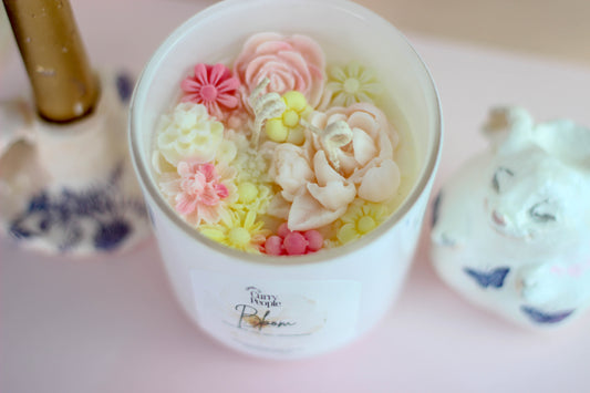A white matte glass jar candle with floral decorations on top, labeled 'Blossom'.