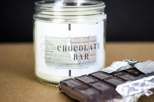 Candle labeled 'Chocolate Bar' with a chocolate bar and foil on a dark background