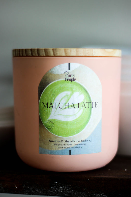 Pink candle with a 'Curry People' label on a dark surface
